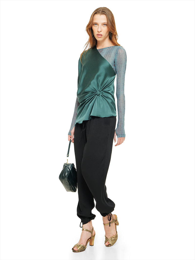 Ganesha top in pine green styled with Boga bodysuit, Luma pants, Margot heels, and Rimba bag, quarter front view - worn by model