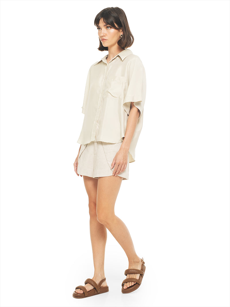 Paris shirt in beige styled with Dian shorts and Charlie flats, quarter front view - worn by model